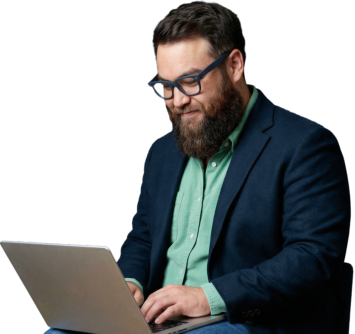 Bearded man wearing glasses and blazer working on a laptop