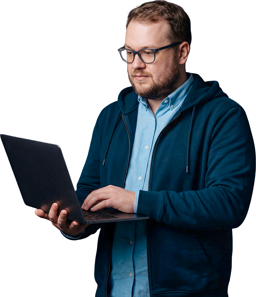 A professional man with glasses and a beard working on a laptop, wearing a navy hoodie